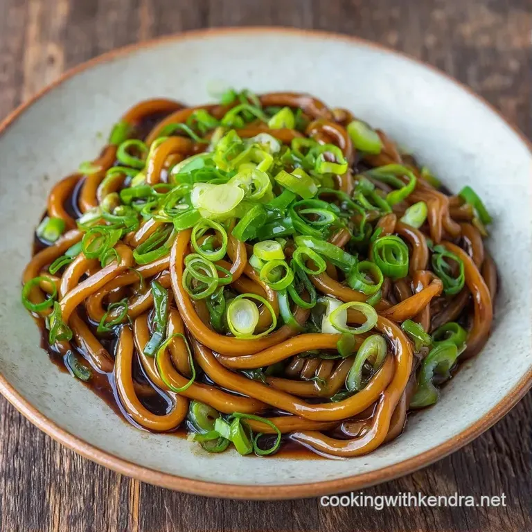 Vibrant stir-fried noodles in a white porcelain bowl topped with sliced green scallions and toasted sesame seeds.