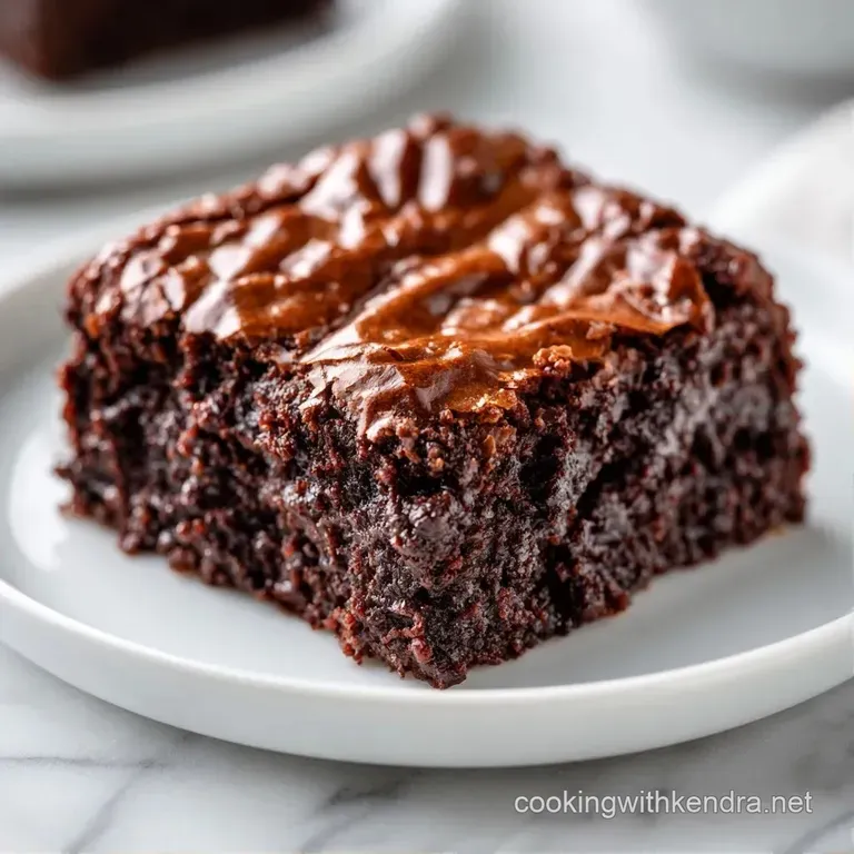 A square of dark cocoa cake dusted with powdered sugar, paired with a dollop of cream and a fresh raspberry.