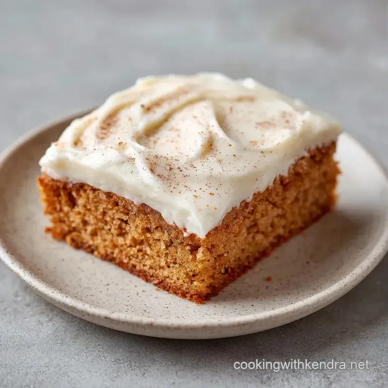 A neat square slice of creamy white cake on a porcelain plate, garnished with a cinnamon stick and fresh mint.