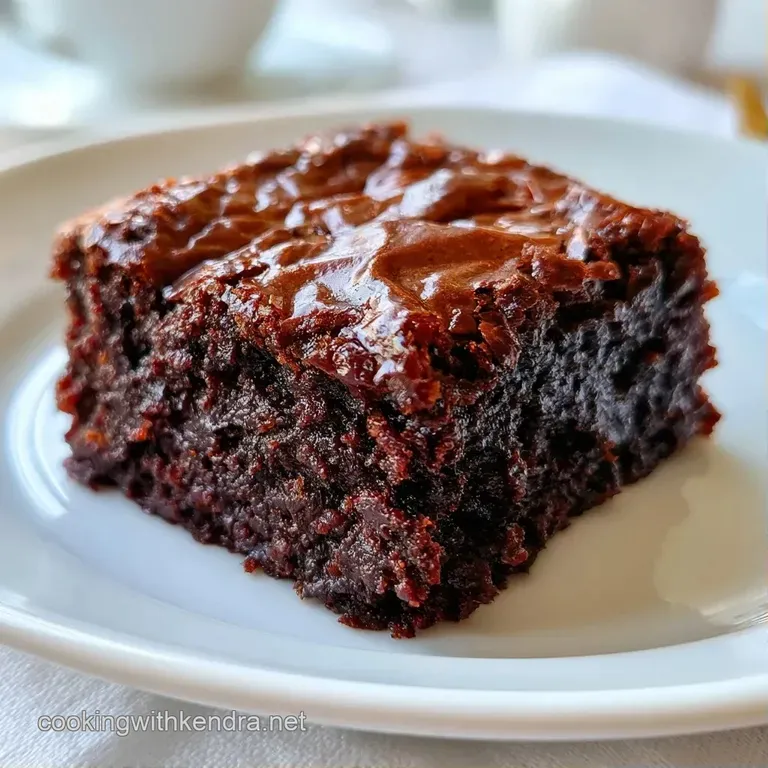 A moist chocolate square dusted with snowy powdered sugar, served on a dark slate plate with a fresh raspberry.