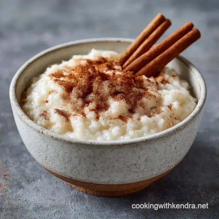 An elegant glass ramekin of thick white pudding garnished with a cinnamon stick and a light dusting of spice.