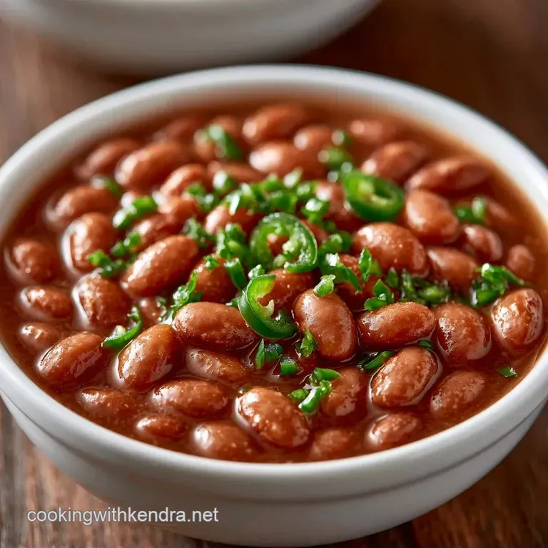 Creamy brown beans in a white bowl topped with diced red onion, fresh avocado slices, and a bright lime wedge.