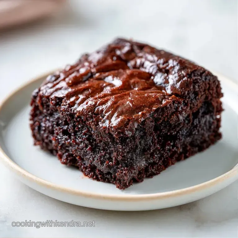 A neat square of moist dark cocoa cake dusted with powdered sugar and served with a swirl of fresh cream.
